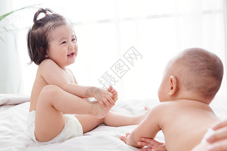 两个可爱宝宝坐在床上玩耍图片