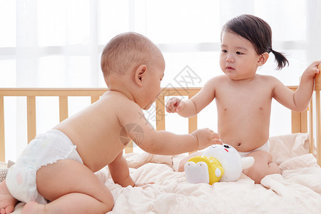 两个可爱宝宝坐在床上玩耍背景图片