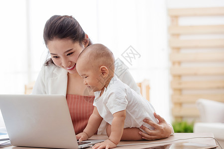 商务人士青年女人东亚年轻妈妈抱着孩子使用电脑图片