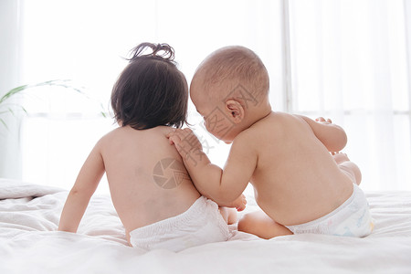 两个可爱宝宝坐在床上玩耍高清图片