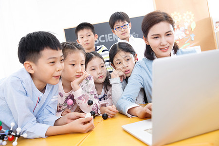 小孩冲浪微笑的童年儿童女教师和小学生在教室里使用电脑背景
