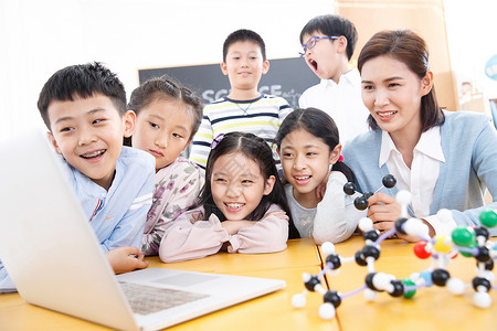 海中冲浪的男孩成长东亚关爱女教师和小学生在教室里使用电脑背景