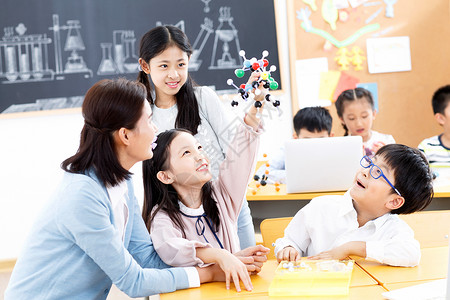 科学指导亚洲休闲装培训班女教师和小学生在教室里背景