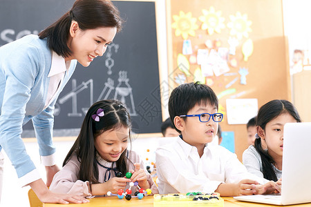 生物课程女教师和小学生在教室里使用电脑背景