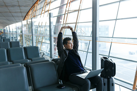 伸懒腰男人笔记本电脑运输旅途商务男士在机场背景