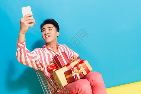 青年人亚洲人表情拿着礼品盒的青年男人看手机图片
