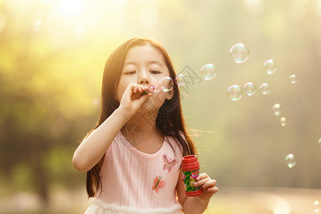 粉色泡泡可爱的女孩在户外吹泡泡背景