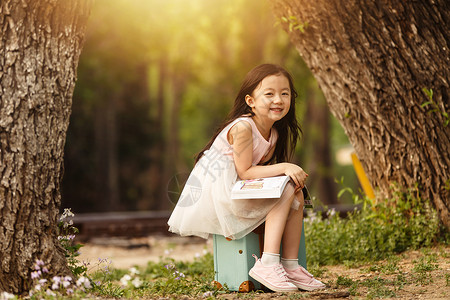 逆光拿书休闲活动水平构图活力可爱的小女孩在户外背景