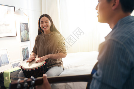 舒适仅成年人20到24岁快乐情侣在家演奏乐器高清图片