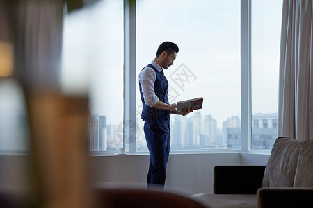 高端商务男士站在窗前看书高清图片