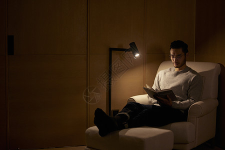 夜晚在沙发上看书的成熟男性高清图片