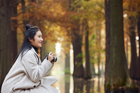 女大学生秋季树林拍照图片