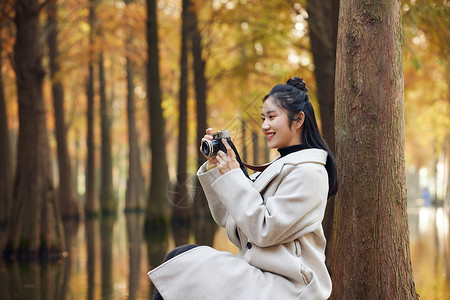 户外美女拿相机拍秋冬风景背景图片