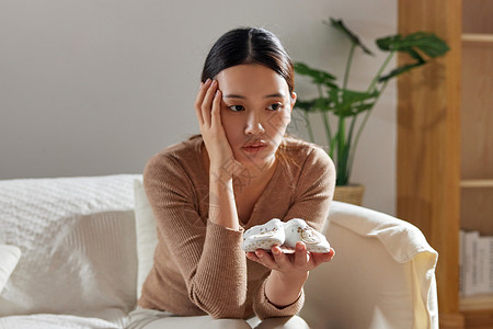 悲伤的妈妈捧着鞋子产后抑郁的宝妈背景