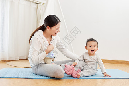 瑜伽垫上妈妈陪宝宝玩耍高清图片