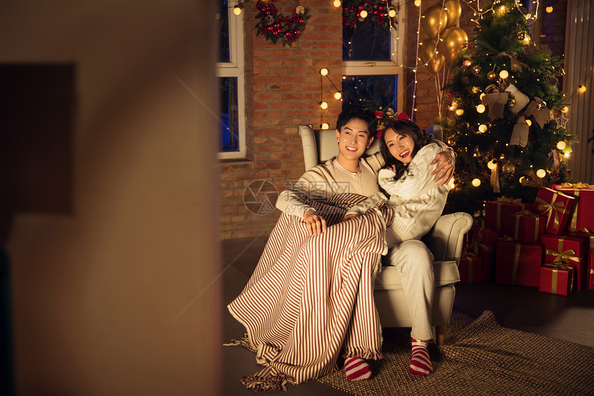 毯子圣诞住宅内部幸福甜蜜的年轻伴侣坐在沙发上图片