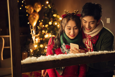 红色青年伴侣陪伴快乐的年轻伴侣在家使用手机图片