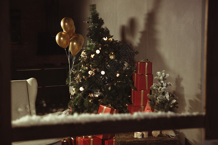 金色窗户礼品盒窗内的圣诞树和圣诞礼物背景图片