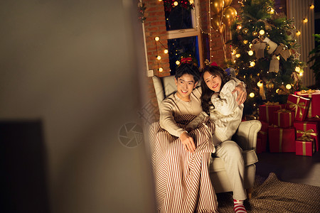 堆叠好的圣诞礼物气球堆叠坐着幸福甜蜜的年轻伴侣坐在沙发上背景