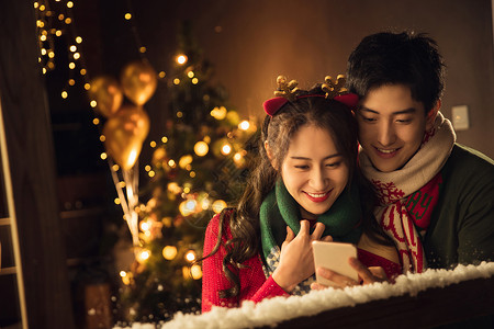 玩雪的人传统节日网上冲浪相伴快乐的年轻伴侣在家使用手机背景
