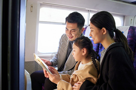 春运出行的一家三口在高铁上看书高清图片