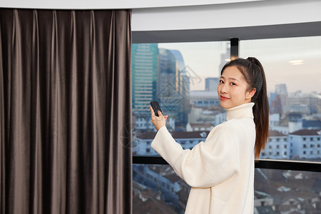居家女性使用遥控开窗帘形象高清图片