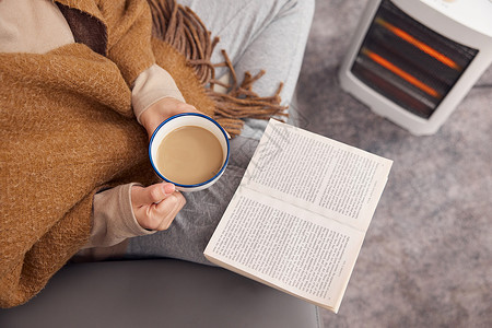 油汀取暖器冬日女性在取暖器旁看书喝咖啡特写背景