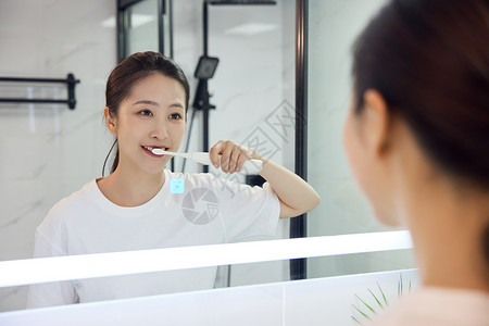 电动牙刷刷牙在洗漱台前刷牙的居家女性背景