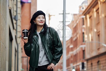 手拿咖啡的青年女性行走街头图片