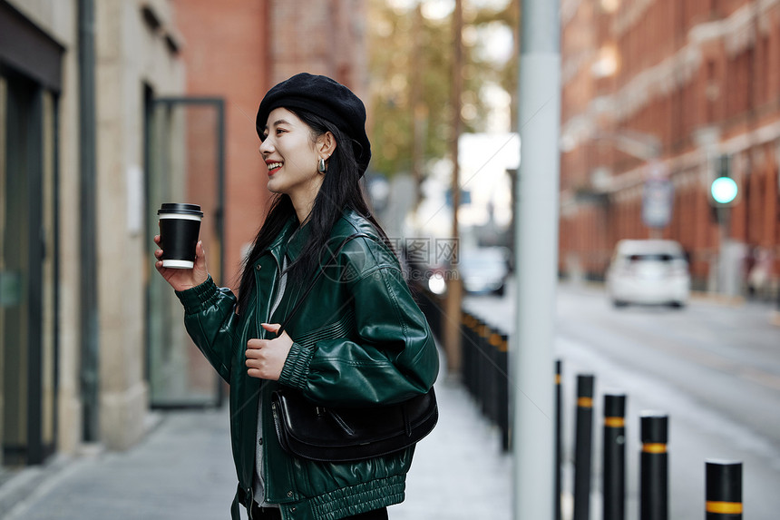 手拿咖啡的青年女性行走街头街拍图片