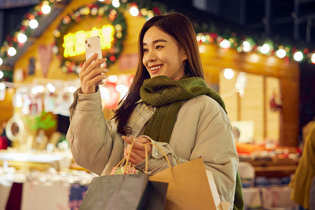 青年女性逛圣诞市集拿手机拍照背景图片