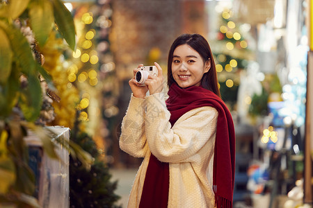 冬季购物手拿相机的青年女性形象背景