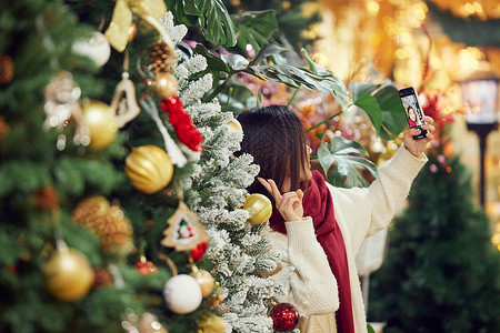 青年女性圣诞采购与圣诞树自拍背景图片