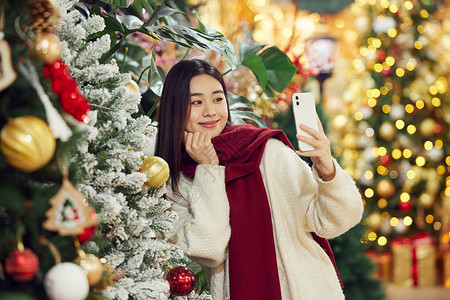 青年女性圣诞采购与圣诞树自拍背景图片