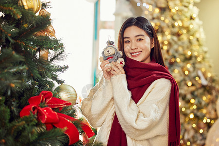 戴围巾的小熊手拿圣诞小熊的青年女性背景