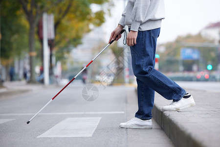 盲人过马路盲人使用盲杖探路过马路特写背景