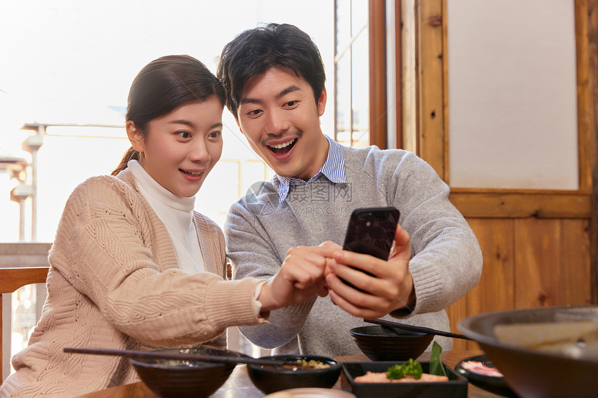 火锅店吃火锅的情侣拿手机抢红包图片