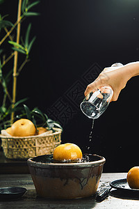 梨子水手拿水杯将水倒在秋月梨上背景