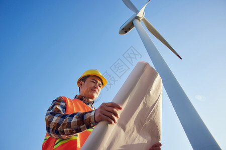 仰拍男性工程师在大风车下看图纸高清图片