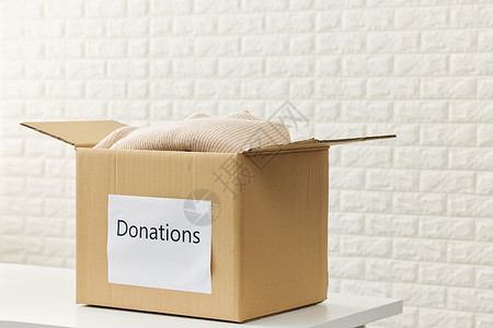 公益献爱心装满旧衣物的捐赠纸盒箱背景