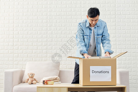 男性爱心捐赠旧衣物打包装箱背景图片