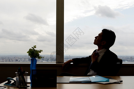 商务男士坐在窗前剪影图片