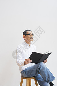 老人坐在凳子上看书图片
