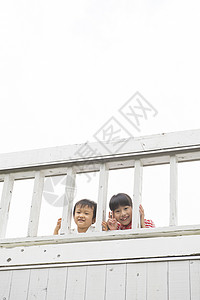 趴在阳台栏杆上的姐弟二人图片