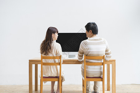 夫妇二人坐在电脑桌前聊天背景图片