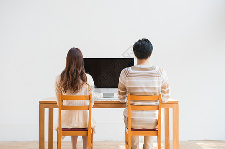夫妻二人坐在电脑桌前图片