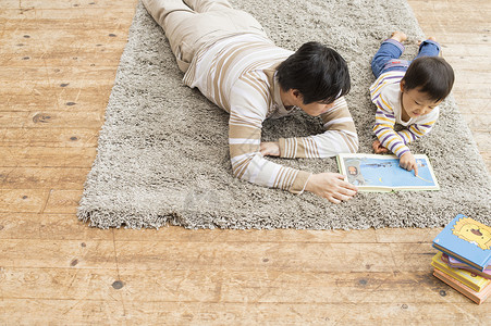 父子躺在地毯上学习图片