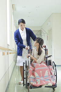 医院走廊上的女护士和轮椅上的小女孩图片