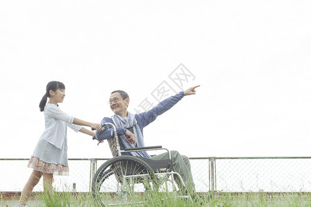 草地上的孙女推着轮椅上的爷爷图片
