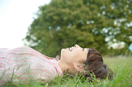 女人躺在公园草地上背景图片